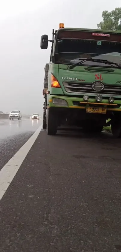 Truck parked on a rainy highway road with misty atmosphere.