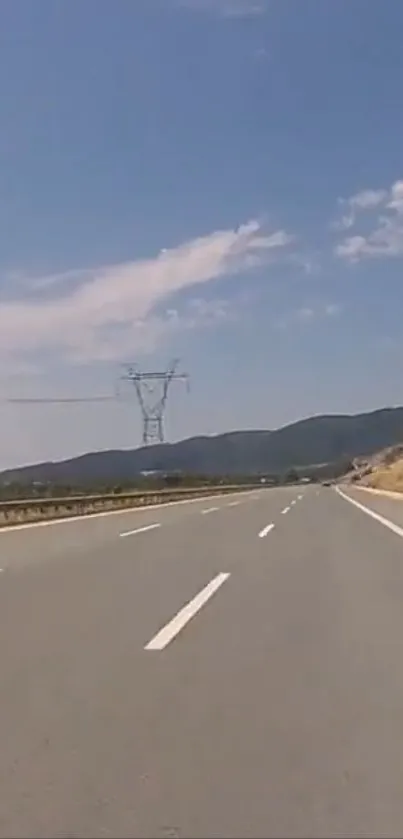 Open highway under clear blue sky with distant mountains.