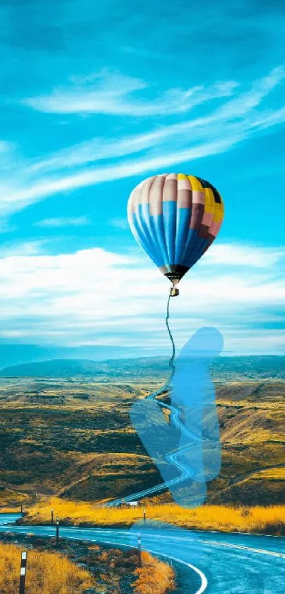 Hot air balloon drifting over a colorful landscape with a winding road.