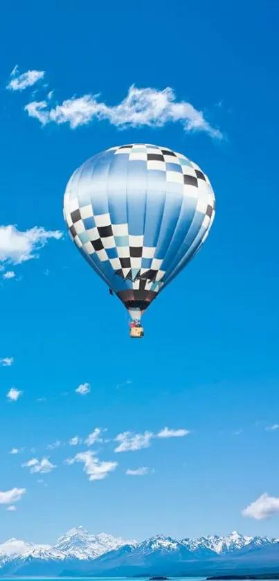 Hot air balloon against blue sky and mountains backdrop.