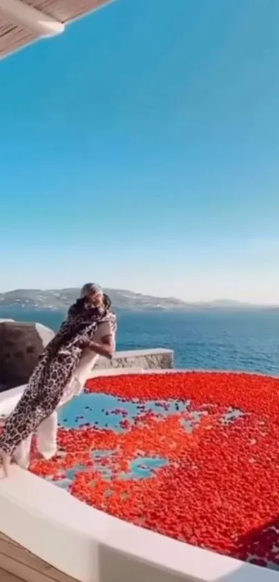 Infinity pool with red petals overlooking a vast ocean under a blue sky.