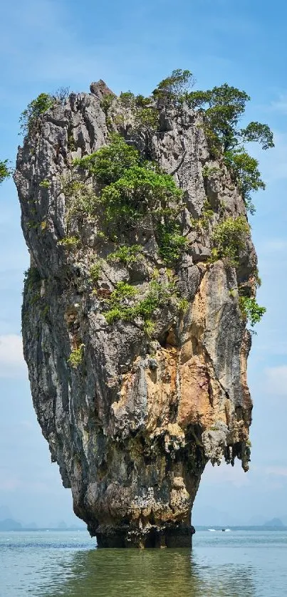 Towering island rock against blue sky and calm water.