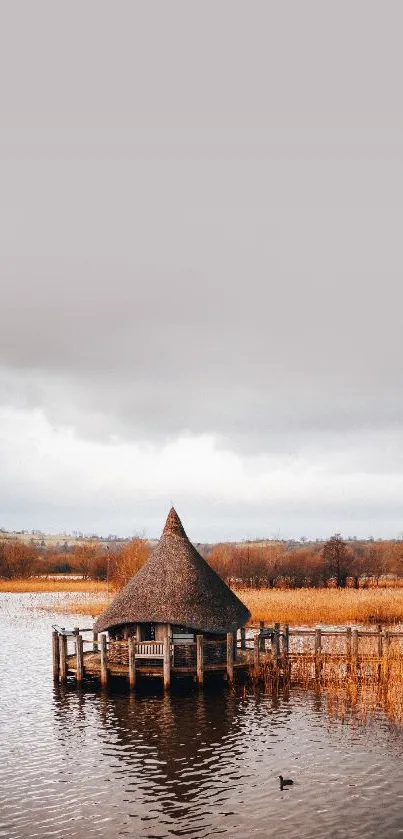 A peaceful lake hut surrounded by tranquil water under a cloudy sky.