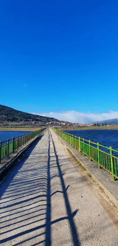 A scenic lake path with vibrant blue skies and green railings under sunshine.