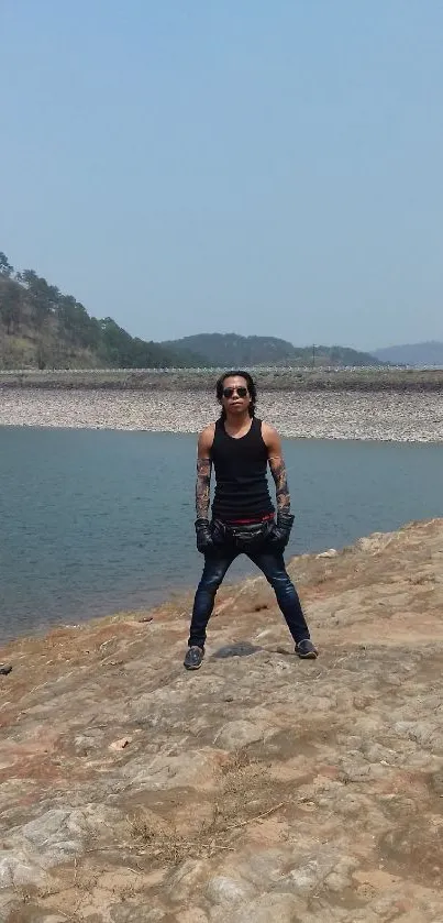 Adventurer standing by a lake with hills in the background.