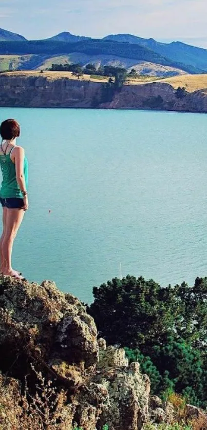 Hiker overlooks a vast blue lake with mountains in the background.