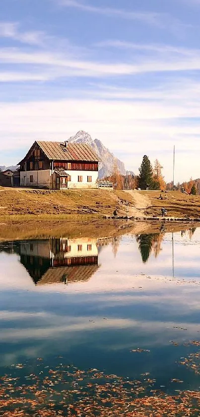 Lakeside house with autumn reflection on calm water under blue sky.