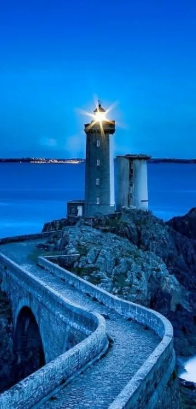 Scenic lighthouse on rocky coast at dusk with a radiant blue sky.