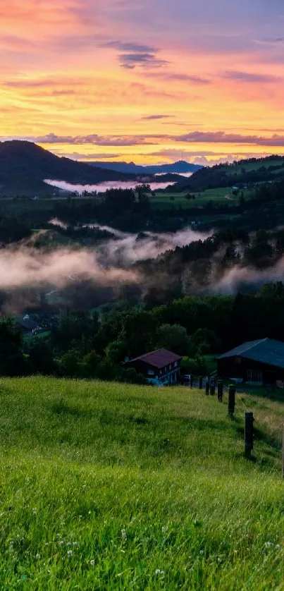 Misty mountain sunrise with green fields and colorful sky.