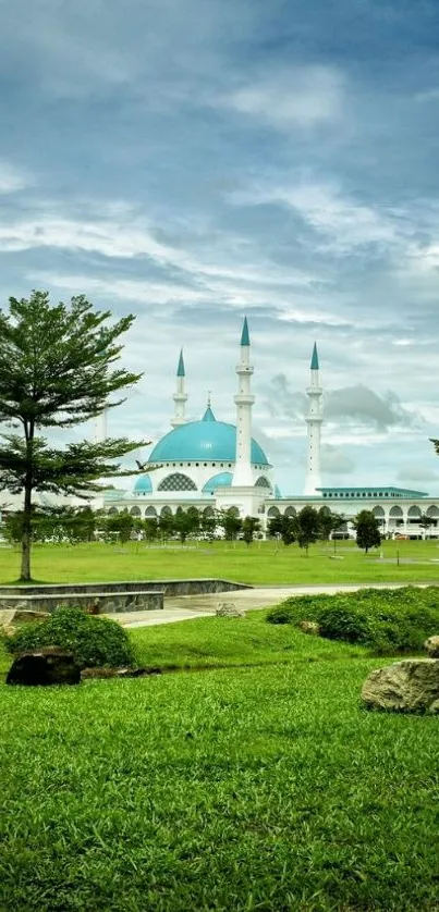 A tranquil mosque under a blue sky surrounded by green grass.