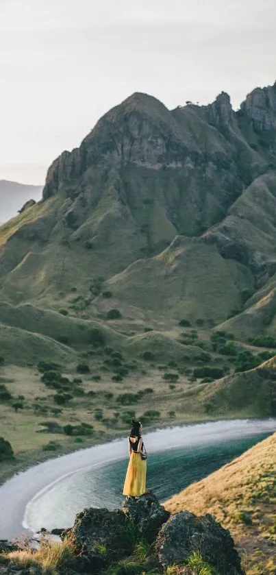 Woman in yellow dress overlooks lush green mountains and a serene bay.