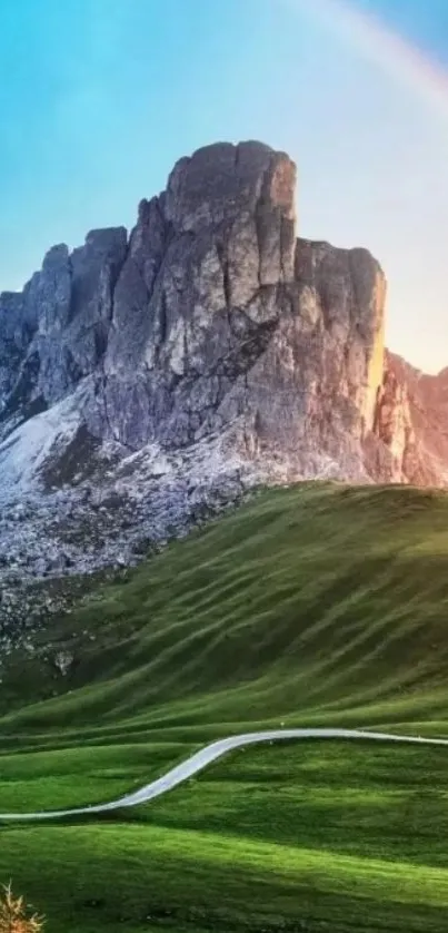 Mountain landscape with rainbow in blue sky.