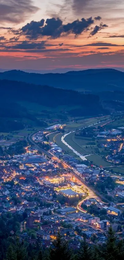 Evening view of a lit-up town nestled in mountains at sunset.