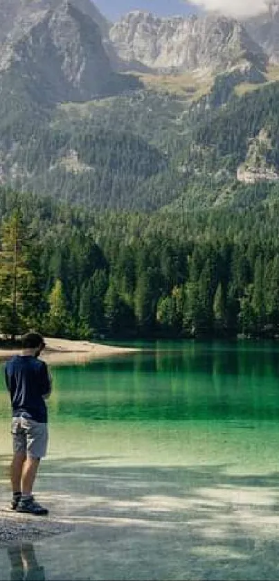 Man admires scenic green lake with mountain backdrop.