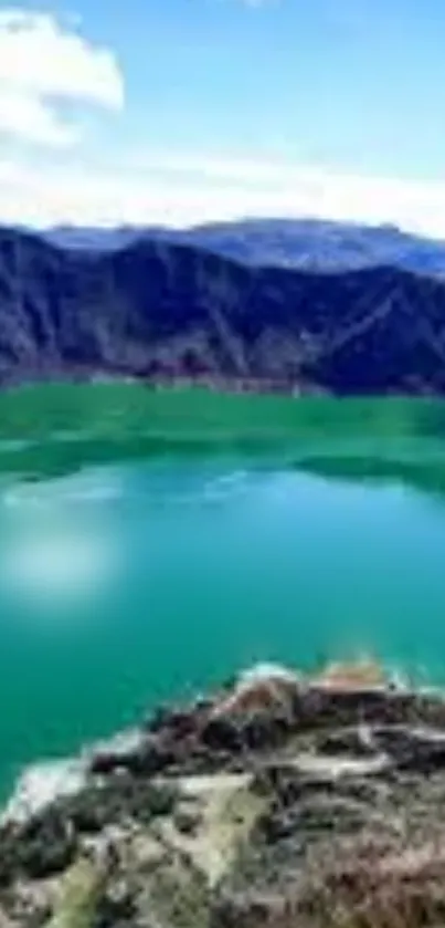 Serene mountain lake with green waters and surrounding hills under a clear blue sky.