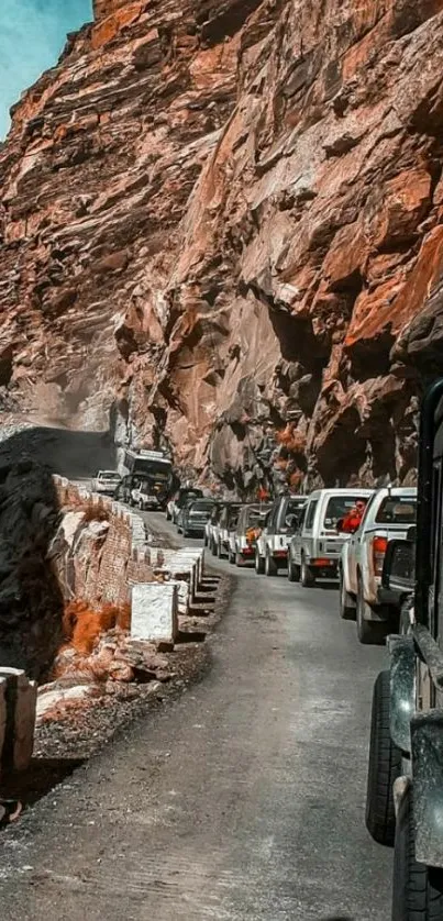 vehicles driving through rugged mountain road with towering cliffs