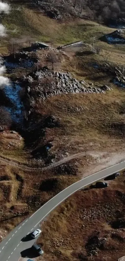 A scenic aerial view of a winding road through a rocky mountain landscape.