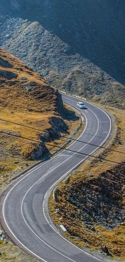 A winding road through scenic mountain terrain under a clear blue sky.