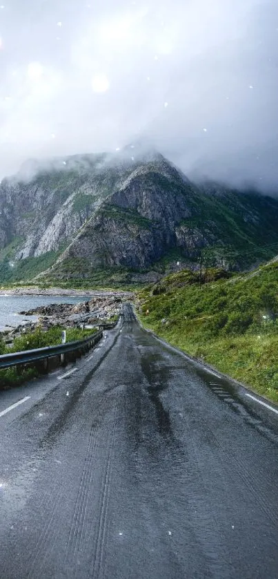 Misty mountain road with lush greenery and clouds.