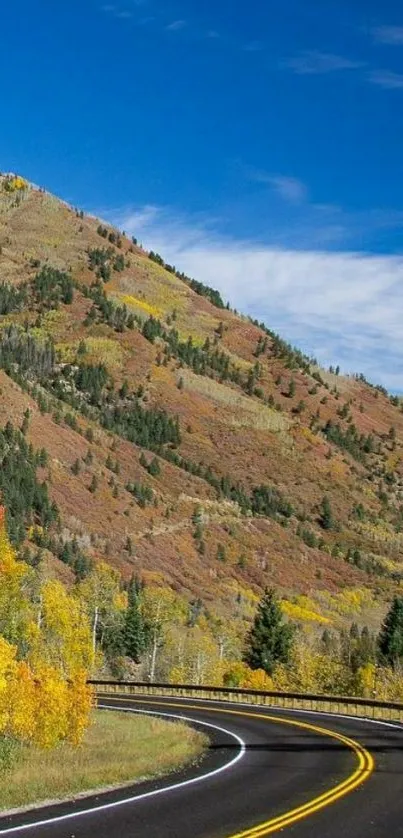 Scenic mountain road in autumn with clear blue sky and vibrant fall colors.