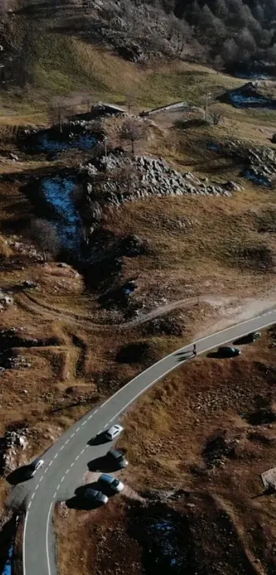 Aerial view of winding road through a rugged mountain landscape, perfect mobile wallpaper.