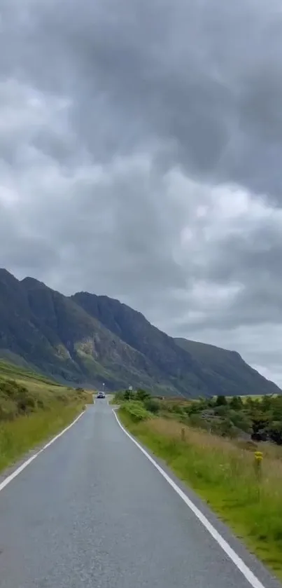 Long road through mountains under cloudy skies.