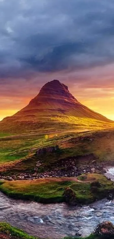 Sunset over mountain with waterfall and lush greenery.