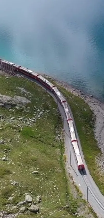 Aerial view of a red train winding through green mountains beside a blue lake.