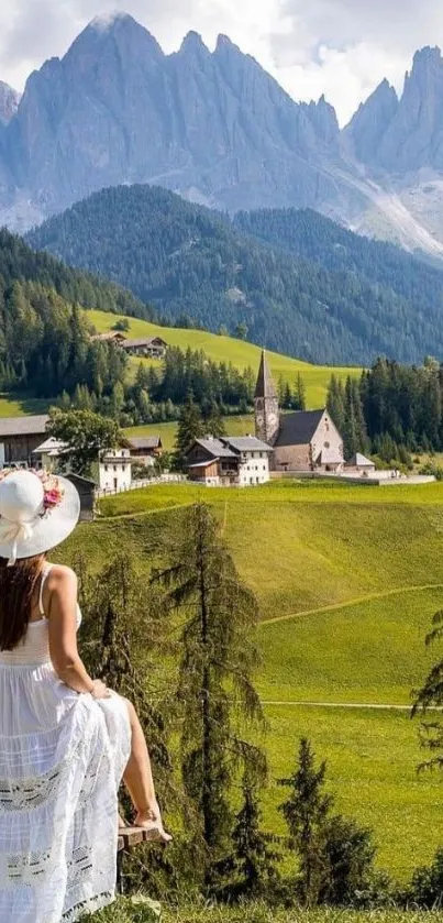 Woman in white dress overlooking mountain village and lush green landscape.