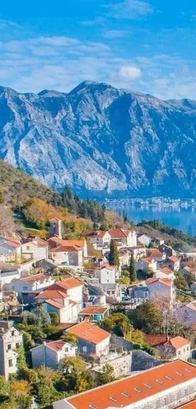 Mediterranean village with red rooftops against mountains and blue sky.