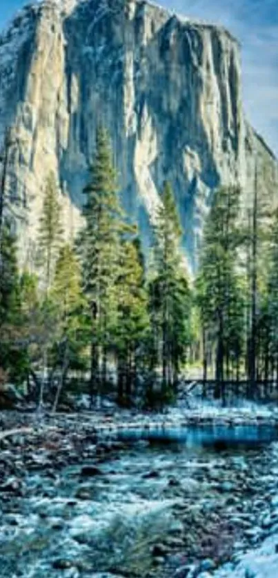 Majestic mountain with trees and river under a blue sky.