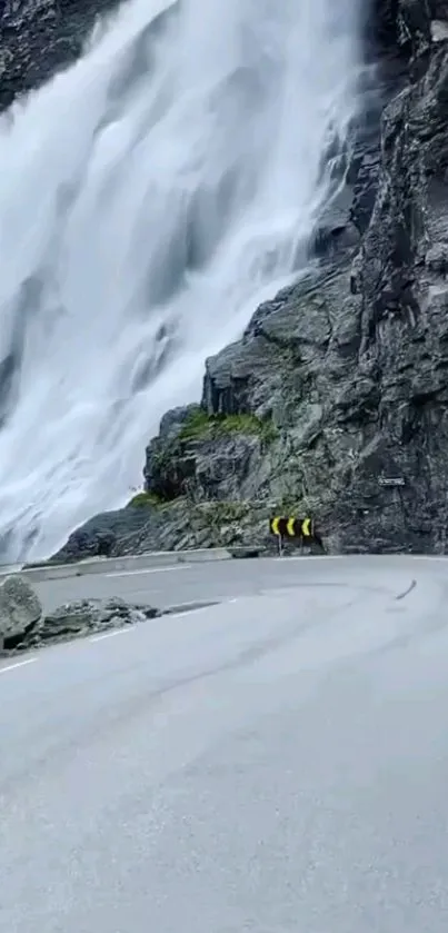 Mountain road with stunning waterfall backdrop.