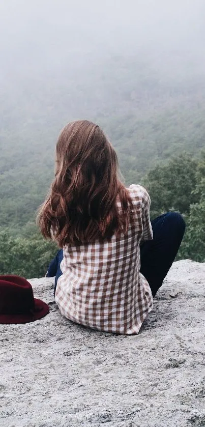 Woman in checked shirt enjoys misty mountain view.