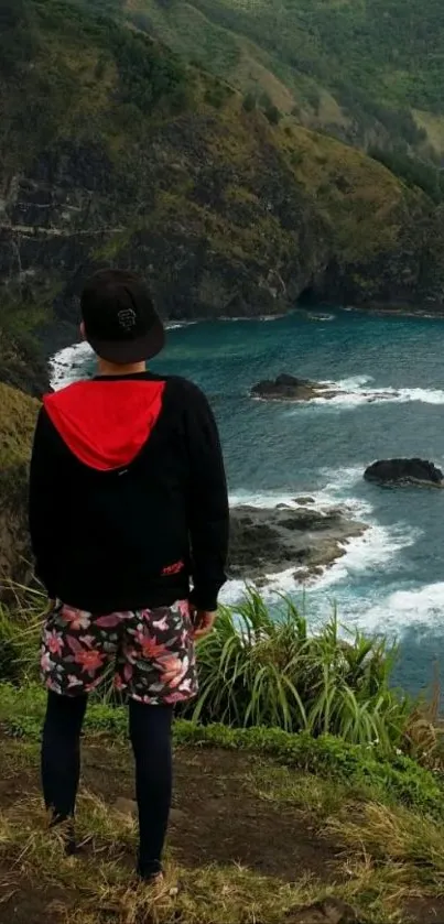 Person standing on cliff overlooking scenic ocean view.