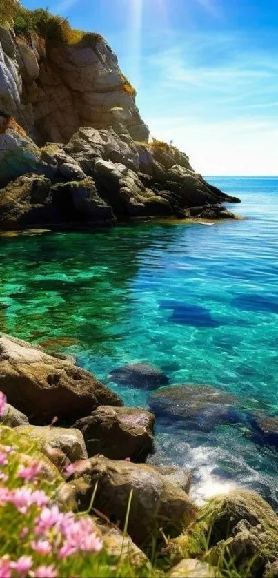 Ocean cliff with clear water and flowers under blue sky.