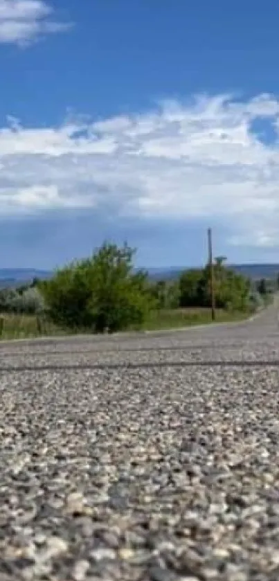 Low-angle view of a long road extending into the horizon under a bright blue sky.