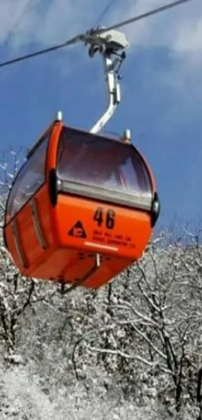 Orange cable car in snow-covered landscape with blue sky.