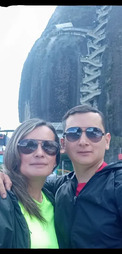 Couple exploring a scenic mountain backdrop with sunglasses on a bright day.