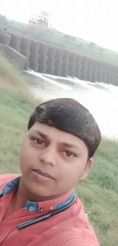 Person near scenic dam amidst lush greenery.