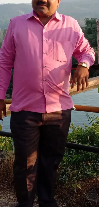 Person in pink shirt with scenic outdoor backdrop.