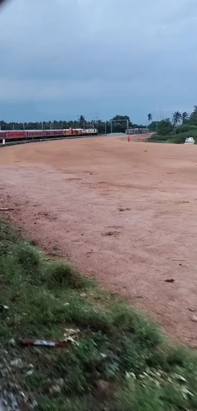 Mobile wallpaper of a train on a rural track with open fields and sky.