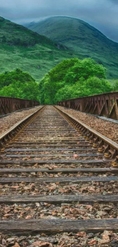 Railway track under green mountains and sky, scenic wallpaper.