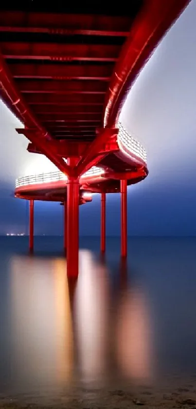 A red pier extends over calm water under a midnight blue sky.