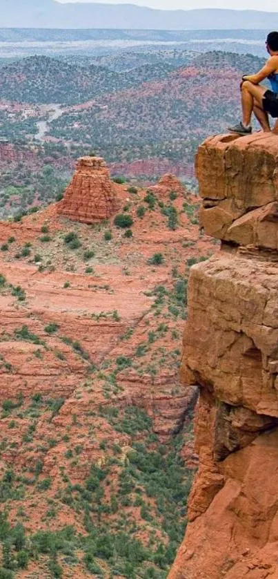 Adventurer on cliff overlooking red rock canyon.