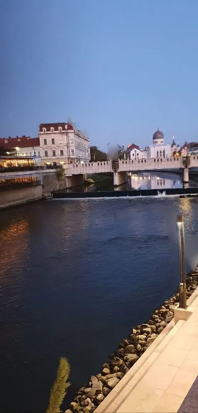 A serene evening city view over a river with a bridge and glowing lights.