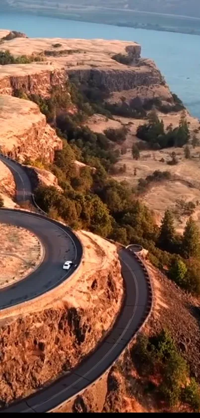 Aerial view of a winding road along stunning cliffs beside a tranquil river.