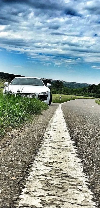 A car on a scenic road with green fields and cloudy sky.