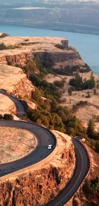 Aerial view of a winding road on a cliff with river in background.