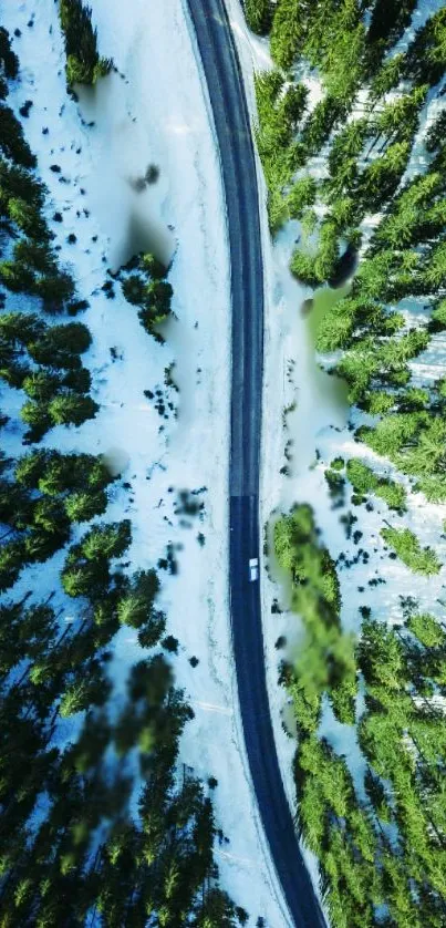 Aerial view of a snowy forest bisected by a winding road.