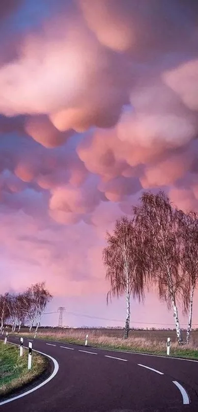 Winding road under pink clouds creating a serene landscape.